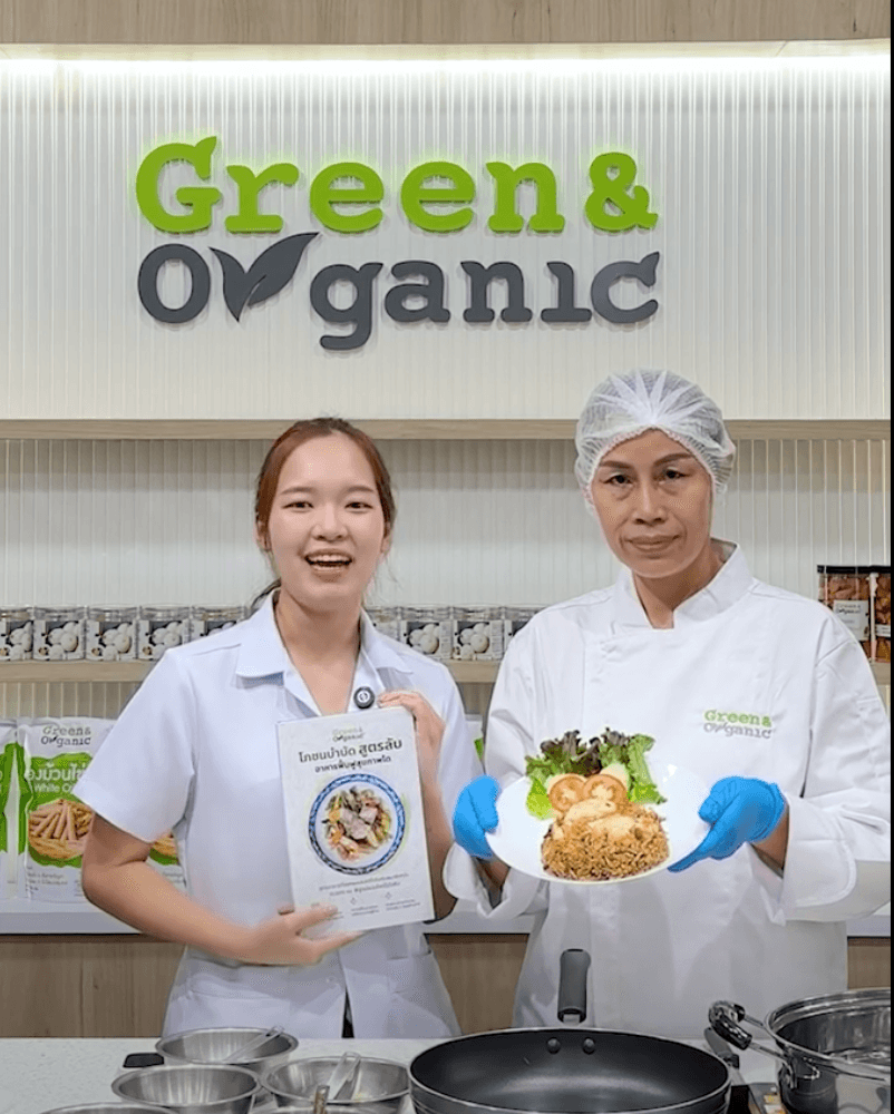 นักโภชนาการ Green & Organic ถือหนังสือโภชนบำบัด พร้อมเชฟถือจานอาหารสุขภาพ หน้าป้าย Green & Organic